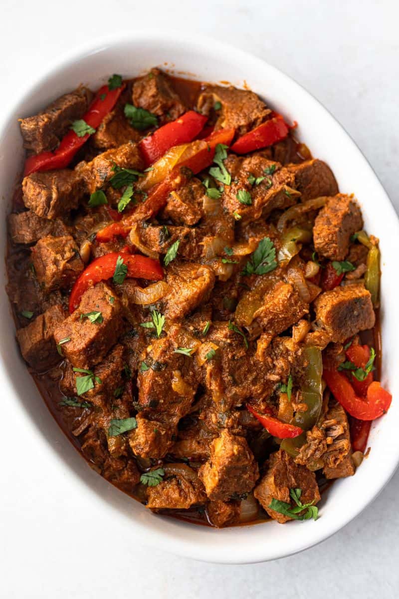 Carne guisada served in an oval dish, topped with fresh cilantro.