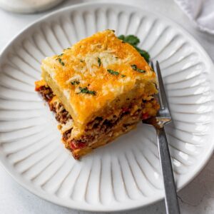 Slice of pastelon de platano maduro (plantain lasagna) on a white plate.