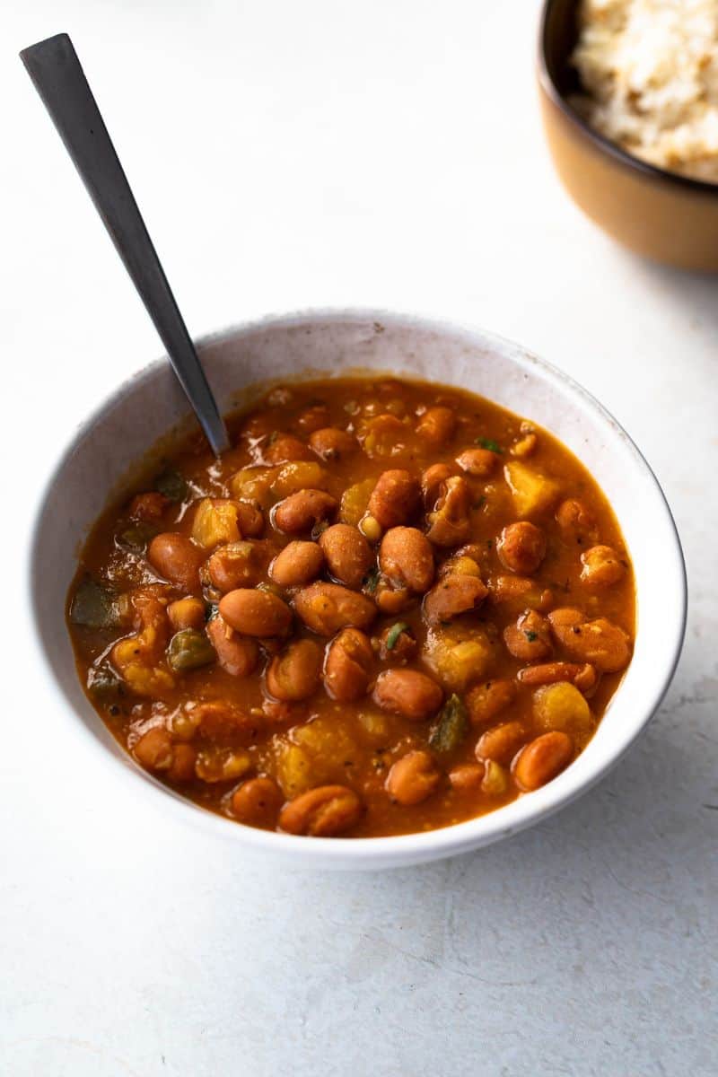 small bowl of Dominican habichuelas guisadas with spoon.