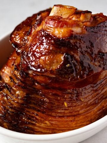 holiday glazed ham with marmalade in a white oval baking dish.
